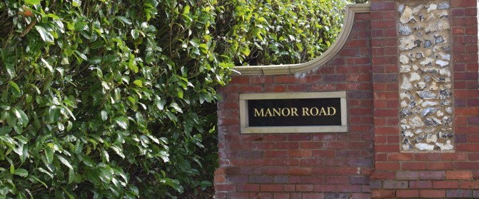 The Manor Road entrance sign, set into a flint and brick wall